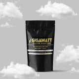 Gigawatt Coffee Cameroonian Mount Oku, smooth and bold Cameroon coffee. Medium dark roast, 3 oz coffee sampler pack, set against a cloud-filled background.